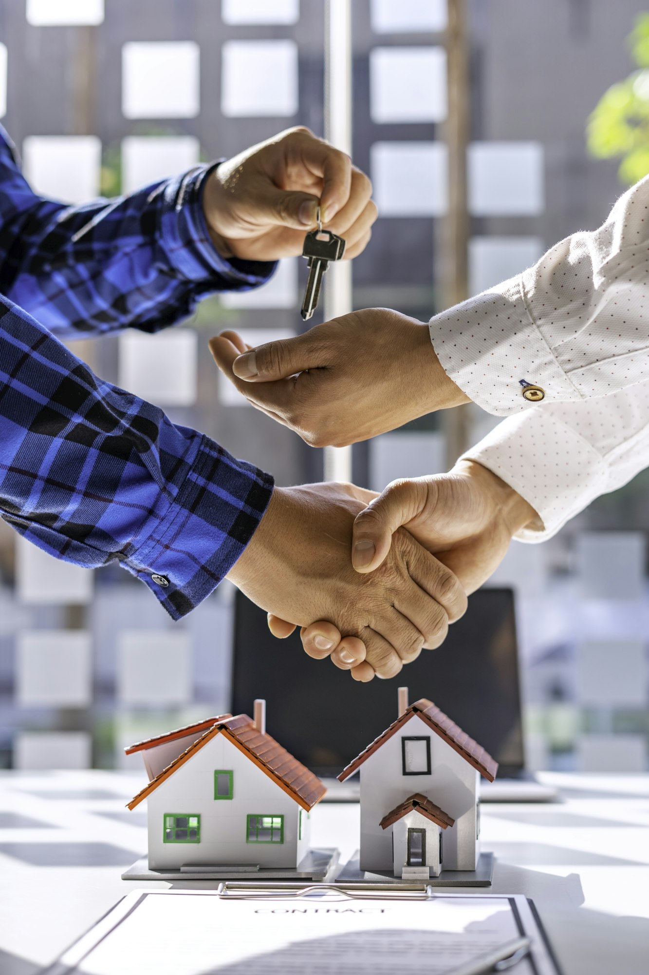 Real estate agents and clients shake hands and deliver the keys. After signing the contract to purch